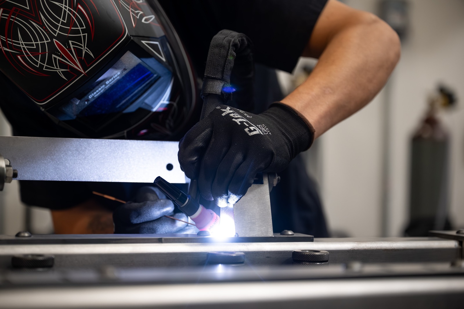 Close-up of a worker welding a vehicle component during manufacturing, representing Ford Motor Company's investment in American manufacturing and electric vehicle production.